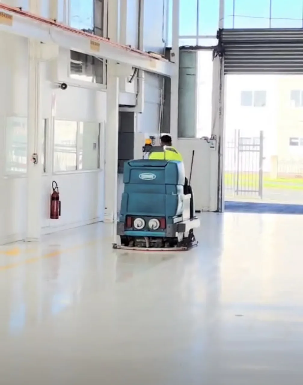 West Maintenance operator using a ride-on floor scrubber in a commercial building