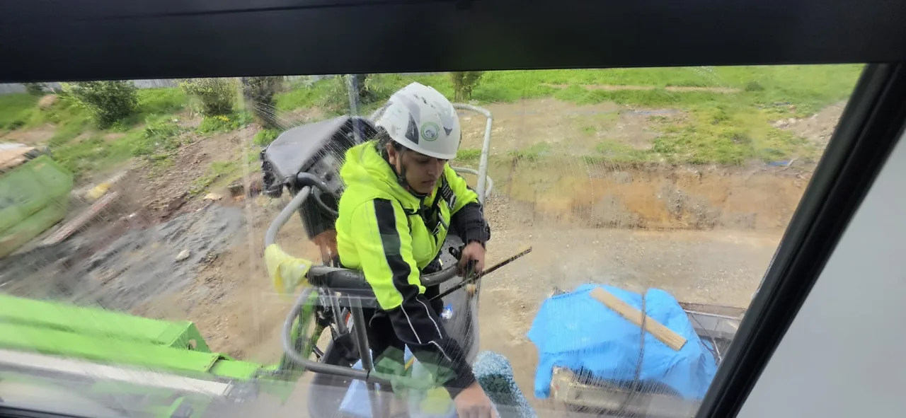 West Maintenance worker cleaning an exterior window from a platform